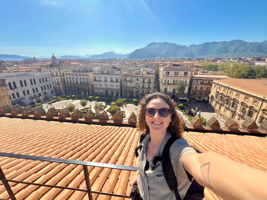 Woman taking a selfie from a rooftop with view of mountains and city in the background