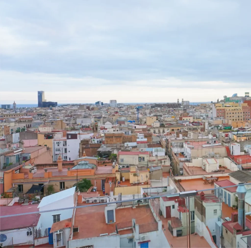 view of terra cotta rooftops in Barcelona from another rooftop with a cloudy sky