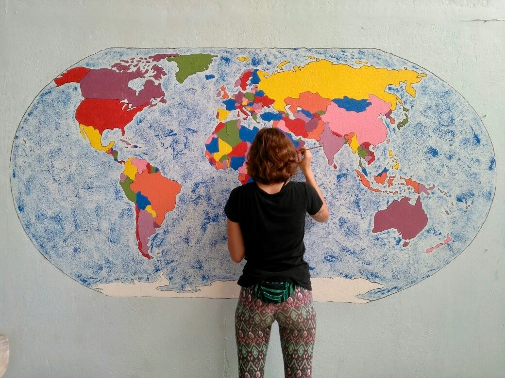 woman standing in front of a mural of a world map