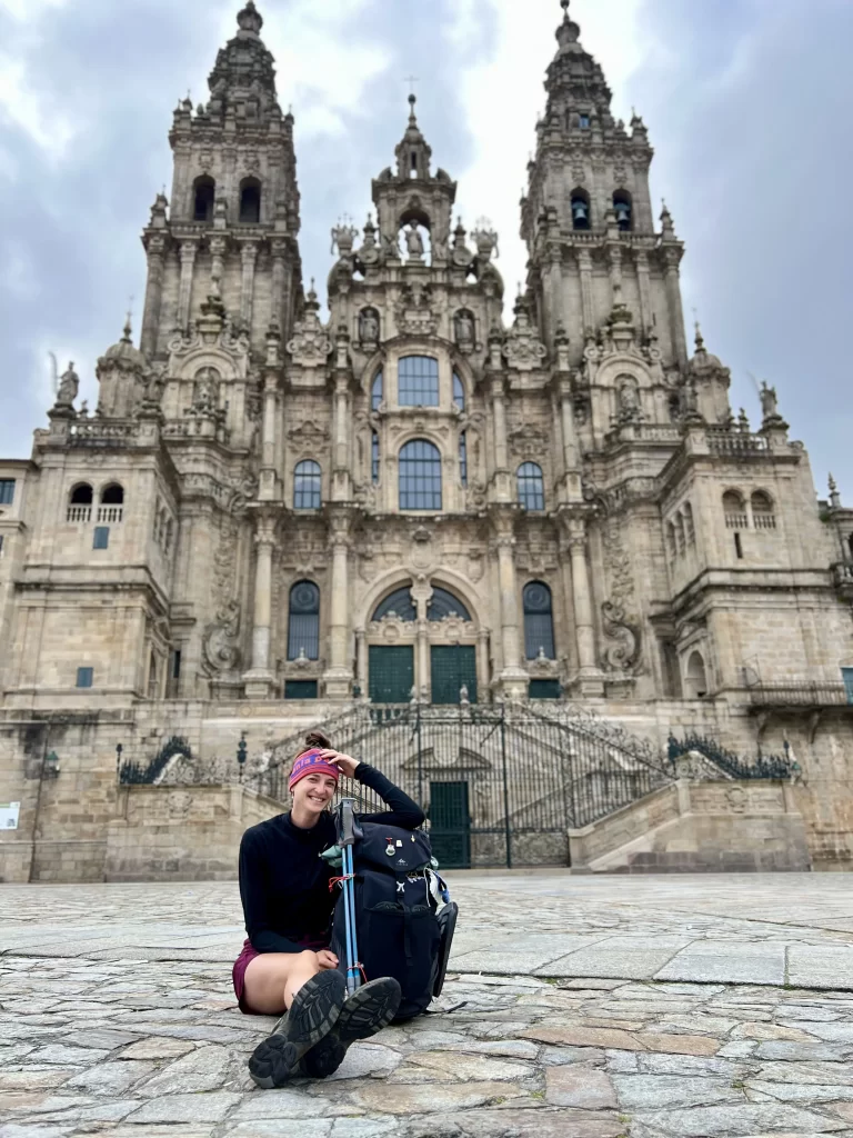 woman sitting with a backpack in front of a large cathedral