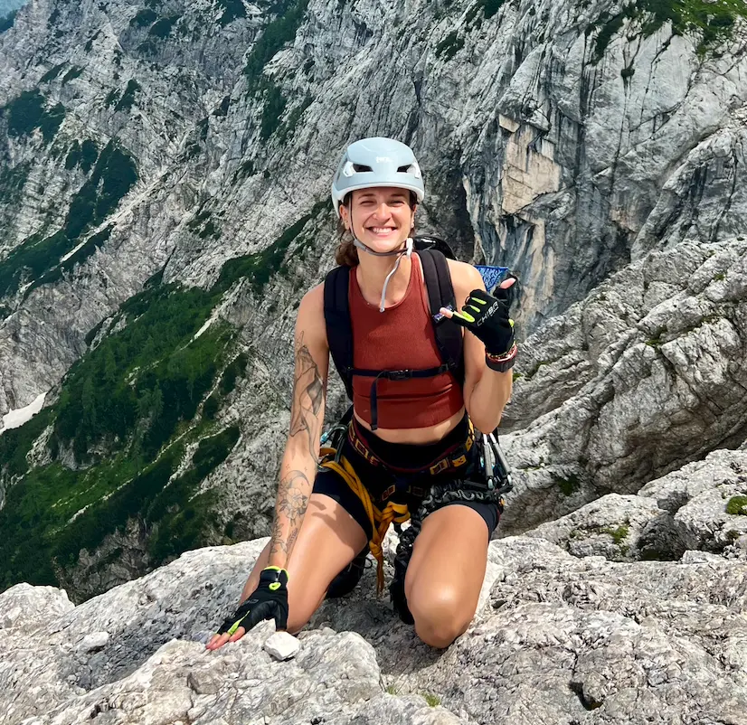 woman with climbing gear sitting on a mountain