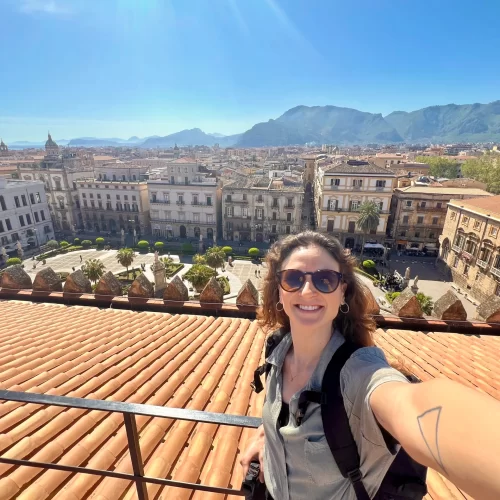 Woman taking a selfie from a rooftop with view of mountains and city in the background