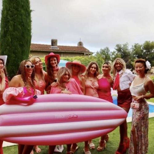 A group of friends dressed in pink standing in front of a pool