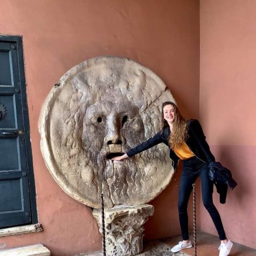 woman placing her hand on a giant marble circular statue